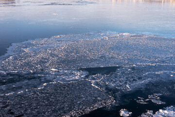 Ice on the river during the ice drift lit by the setting sun in the spring