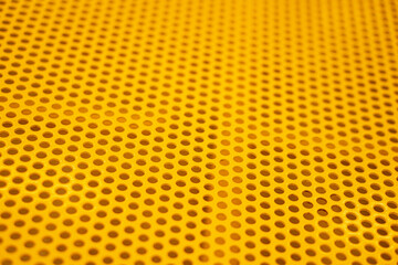 Yellow plate of steel with regular pattern of holes 