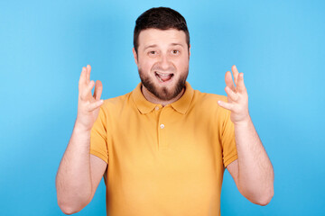 Angry brunette man screaming, rage and mad expression. Isolated on blue background.