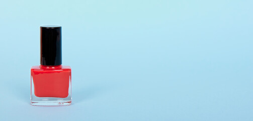 Red nail polish bottle, make up. Isolated on blue background, copy space.