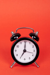 Classic analog clock with bells. Isolated on red background. Copy space.