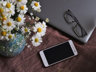 notebook and flowers, working from home with a style, office, home office of business lady. desk with flowers. laptop, cellphone and white flowers, chamomile bouquet 