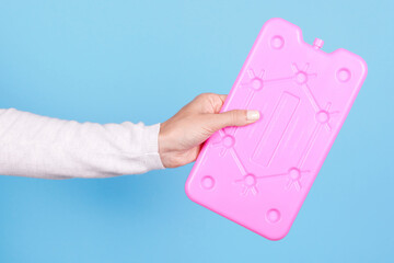 Hand with pink ice cooler, portable refrigeran. Isolated on blue background.