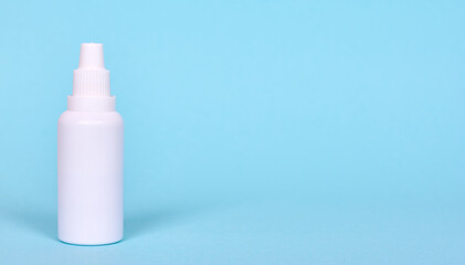 Nasal spray, drops in white bottle. Isolated on blue background, copy space template, banner.