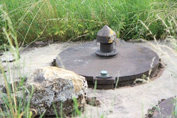 Alter Brunnendeckel Deckel eines Brunnen Wasserbrunnen mit großem Stein Felsen