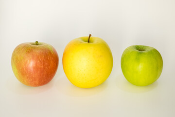 Three different types of apples are aligned horizontally on a white background, the concept of An apple a day takes the doctor away.