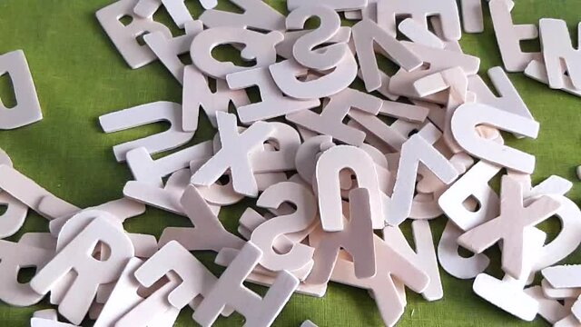 Lettere dell'alfabeto inglese di legno cadono dall'alto. Rallentatore