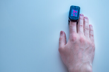 pulse oximeter is placed on the index finger of a man’s hand to measure saturation. Close-up.