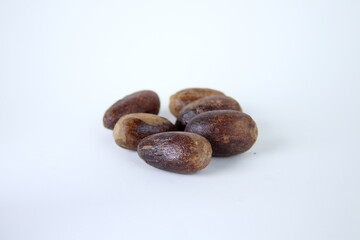 Dark brown whole seeds of nutmeg and white background.