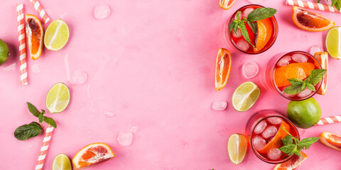 Pink background with ingredients for summer iced red cocktail with blood orange and lime. Banner