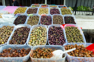 Bowls of various olives for sale at an open street market. Different kinds of mediterian olives on a counter. Street food market.