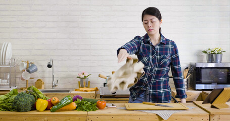 young asian woman in angry upset and frustrated face expression while throwing apron on ground. housewife with stress lifestyle concept. mad female standing at wooden kitchen island and quit to cook