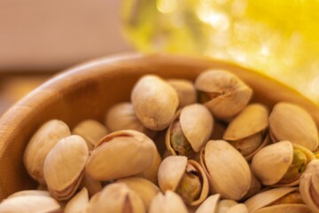 detail of a wooden bowl full of pistachio nuts appetizers on a simple wooden table with a lemonade on a hot day