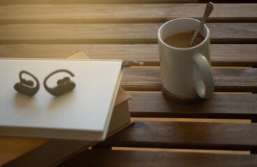 books and wireless headphones on a wooden table with a relaxing coffee