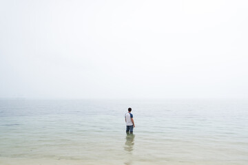 Fototapeta na wymiar Man stood in water with fog on horizon 