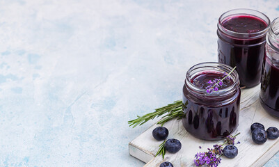 Blueberry, lavender and rosemary jam or marmalade on light wooden cutting board, blue concrete...