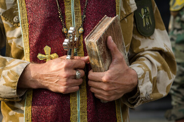 Prayer-book in and big orthodox cross in the hands of ukrainian military orthodox сhaplain