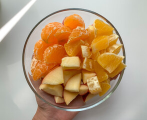 Sliced fruit, tangerine, orange, Apple in a glass plate on a white background. Proper food, vegetarianism. Vitamins, strengthen the immune system.
