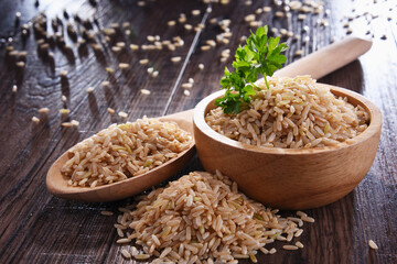 Composition with bowl of brown rice on wooden table - obrazy, fototapety, plakaty