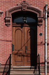 Vintage shabby-looking entry door in New York decorated with arch and corbels. USA.