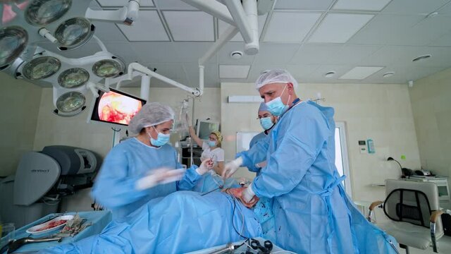 Surgery in the operating theater. Teamwork of medical specialists conduct an operation to a patient on the background of modern medical equipment in clinic.