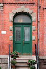 Green vintage shabby-looking double entry door decorated with arch and rustication. New York. USA.