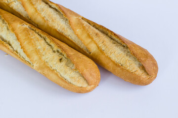 Fresh baguette breads on white surface with knife,above view.