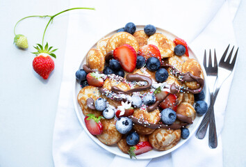 Little pancakes. Dutch poffertjes with blueberries  and strawberries .