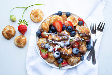 Little pancakes. Dutch poffertjes with blueberries  and strawberries .