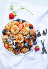 Little pancakes. Dutch poffertjes with blueberries  and strawberries .