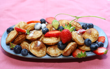 Little pancakes. Dutch poffertjes with blueberries  and strawberries .