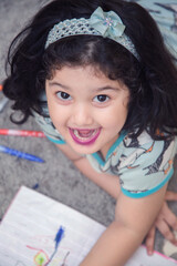 Indian Asian preschooler Schoolgirl With Pile Of Books studying online class at home.