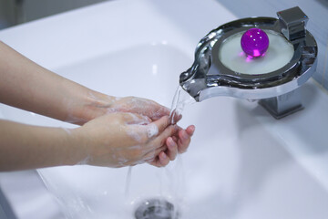 woman washing hands in bathroom with soap