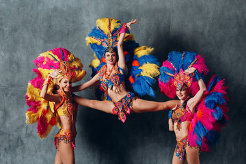 Three Woman in cabaret costume with colorful feathers plumage.