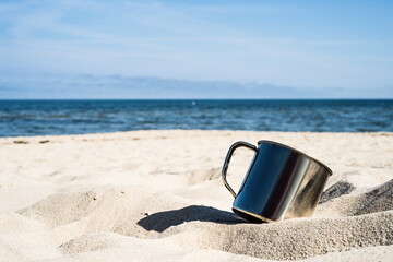 Fototapeta na wymiar steel tourist mug, sandy beach, Baltic Sea