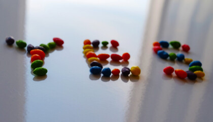 The inscription YES, inlaid with multicolored dragees on a light, shiny surface.