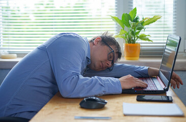 Tired of hard work  guy sleeping on laptop at table