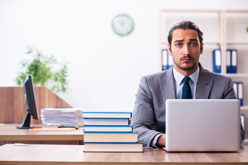 Young male businessman reading books at workplace