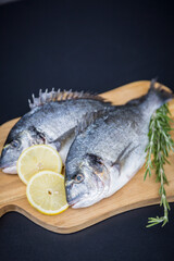 Frische Dorade auf Holzbrett mit Rosmarin und Zitrone