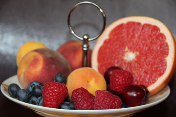 Fruit and berry plate on a dark background. Juicy summer berries and fruits
