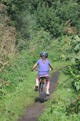 Young girl riding a bicycle on a path in the woods