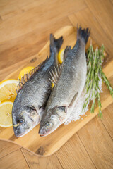 Frische Dorade auf Holzbrett mit Rosmarin und Zitrone