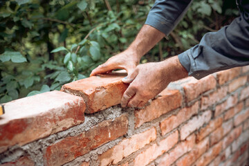 Construction bricklayer worker building with bricks, mortar, trowel. Industrial construction site...