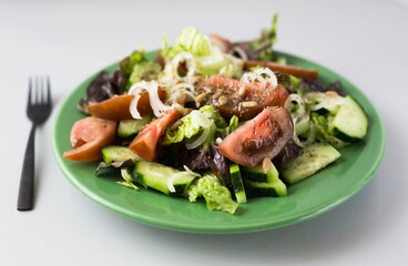 vegetable salad of greens, tomatoes and cucumbers on a green plate