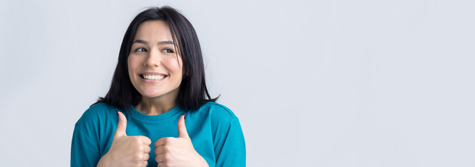 Happy young caucasian female in a blue t-shirt making thumb up sign and smiling. Good job and respect.