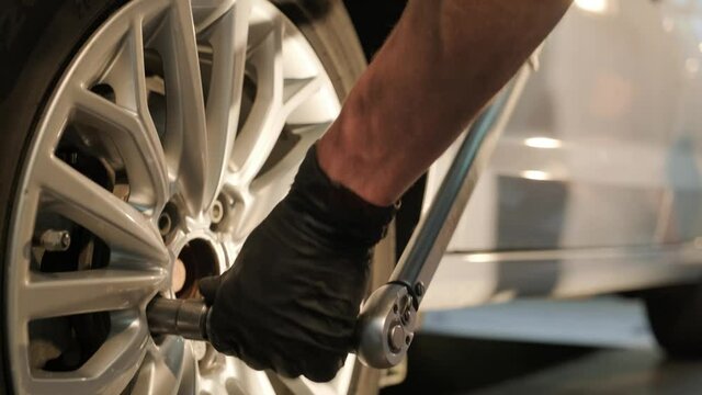Car mechanic replacing a car tire in garage workshop. Slow motion. Auto service