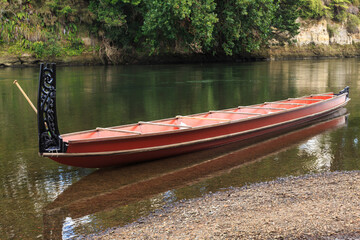 A Maori waka (canoe) with ornamental carvings on the stern post in the Waikato River, New Zealand