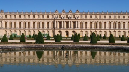 Fototapeta na wymiar Château de Versailles vu du jardin, aile du Midi et son reflet dans l'eau du bassin du parterre du Midi (France)