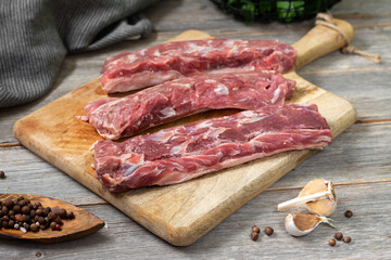 Lamb meat. A young lamb on a wooden Board on a gray wooden kitchen table. Lamb meat and cooking ingredients. The view from the top	