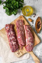 Lamb meat. Young lamb meat on a wooden Board on the light gray kitchen table. Raw lamb meat and cooking ingredients. Lamb tenderloin	